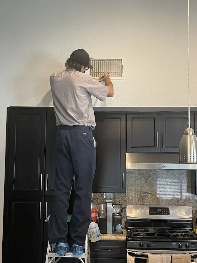 Technician inspecting an air vent during HVAC service in Horsham